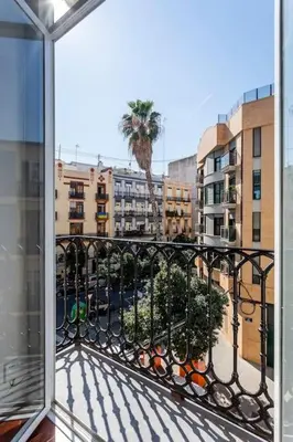 a balcony with a view of a palm tree and buildings at 7P céntrico piso con encanto in Valencia