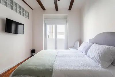 a white bedroom with a large bed and a television at 7P céntrico piso con encanto in Valencia