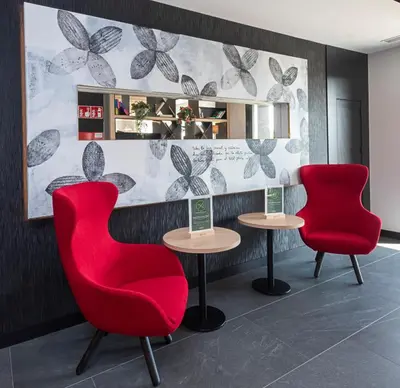 two red chairs and two tables in a room at Sercotel Plana Suites in Vall de Uixó