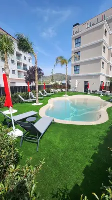 a swimming pool with chairs and a building at Sercotel Plana Suites in Vall de Uixó