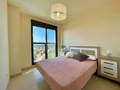 a bedroom with a bed and a large window at Apartamento con piscina, padel y vistas al mar in Moncófar
