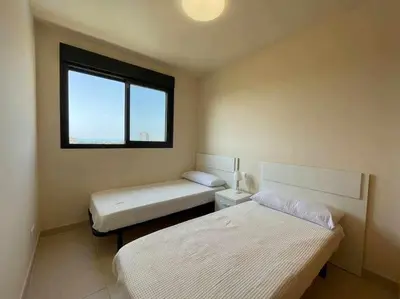 a bedroom with two beds and a window at Apartamento con piscina, padel y vistas al mar in Moncófar
