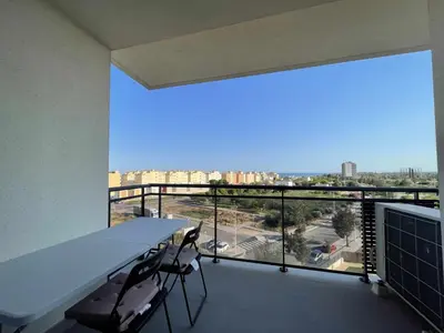 a balcony with a table and chairs and a large window at Apartamento con piscina, padel y vistas al mar in Moncófar