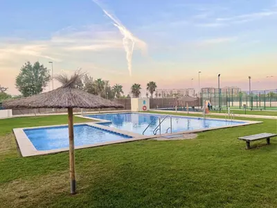 a swimming pool with an umbrella and a bench at Apartamento con piscina, padel y vistas al mar in Moncófar