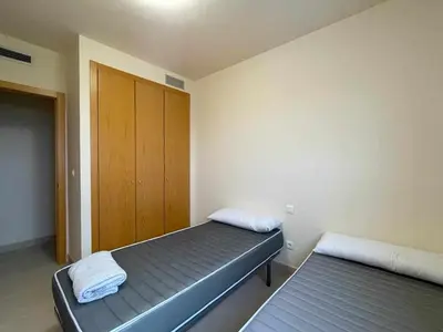 a bedroom with two beds and a wooden door at Apartamento con piscina, padel y vistas al mar in Moncófar