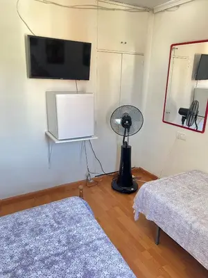a room with two beds and a flat screen tv at Malvarrosa habitación cómoda y sencilla cerca de la playa in Valencia