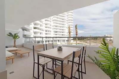 a dining room with a table and chairs and a building at Global Vacacional, Apartamento con terraza y vistas a la piscina en Gran Canet in Canet de Berenguer