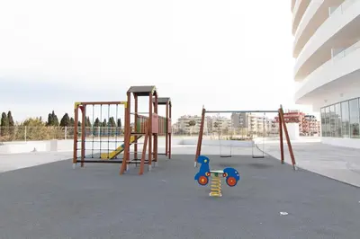 a playground in a building with a swing set at Global Vacacional, Apartamento con terraza y vistas a la piscina en Gran Canet in Canet de Berenguer