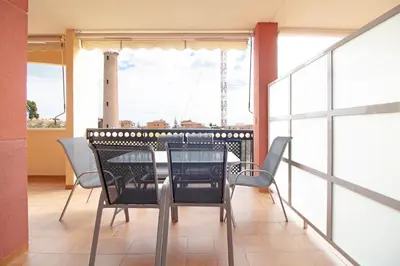 a dining room with a table and chairs on a balcony at Global Vacacional, Apartamento con terraza y piscina en la playa de Canet in Canet de Berenguer