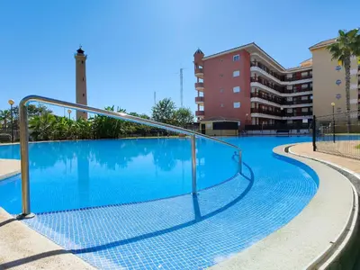 a swimming pool with a metal handrail next to a building at Global Vacacional, Apartamento con terraza y piscina en la playa de Canet in Canet de Berenguer