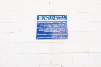 a sign on the side of a white brick wall at Tu refugio en Canet, piscina, parking y playa in Canet de Berenguer