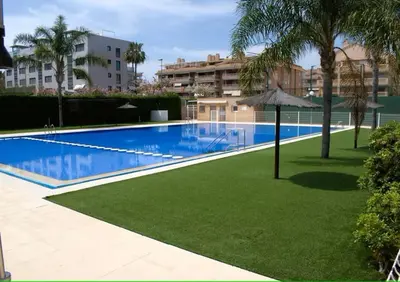 a large swimming pool with an umbrella in a yard at Exclusivo apartamento en Canet in Canet de Berenguer