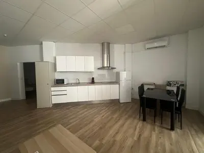 a room with a table and a kitchen with white cabinets at Apartamento tipo loft valencia in Paiporta