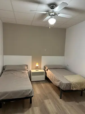 two beds in a room with a ceiling fan at Apartamento tipo loft valencia in Paiporta