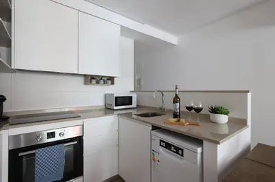 a kitchen with white cabinets and a counter with wine glasses at FLORIT FLATS - The Apolo Apartment in Valencia