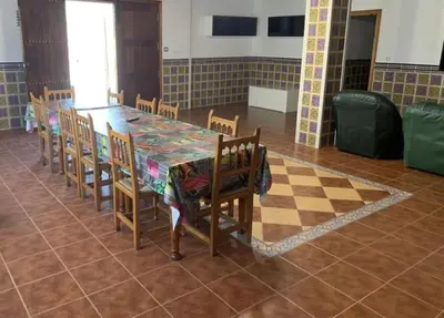 a dining room with a table and chairs and a checkerboard floor at El-cortijo in Siete Aguas