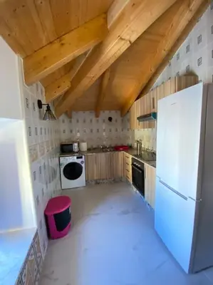 a kitchen with a white refrigerator and wooden ceilings at La carchata ático in Siete Aguas