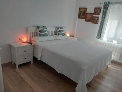 a white bedroom with a white bed and a night stand at Family Apartment Andrea in Alaquas