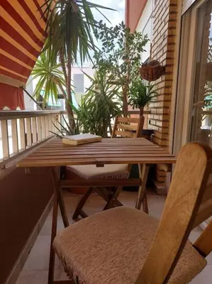a wooden table and chairs on a balcony with plants at Family Apartment Andrea in Alaquas
