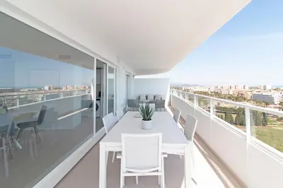 a white dining room with a table and chairs on a balcony at Moderno apartamento con vistas a la costa mediterranea en Gran Canet in Canet de Berenguer