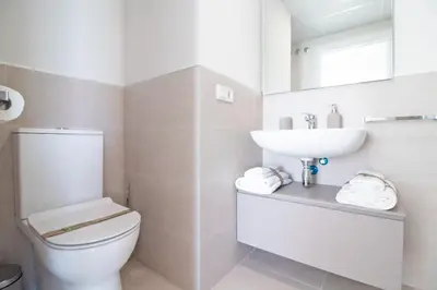 a white bathroom with a toilet and a sink at Moderno apartamento con vistas a la costa mediterranea en Gran Canet in Canet de Berenguer