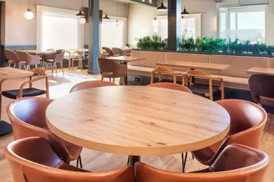 a cafeteria with wooden tables and chairs at B&B HOTEL Valencia Aeropuerto in Paterna