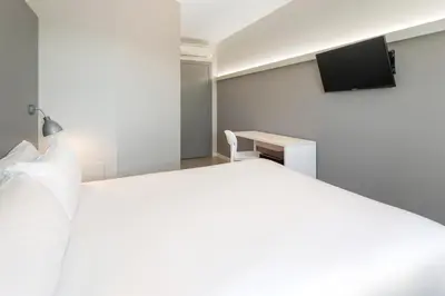 a bedroom with a white bed and a tv at B&B HOTEL Valencia Aeropuerto in Paterna