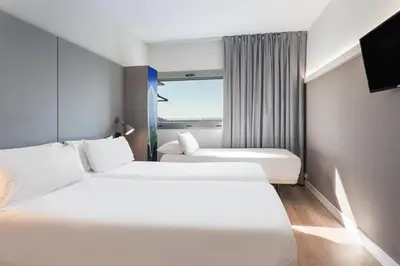 a hotel room with two beds and a window at B&B HOTEL Valencia Aeropuerto in Paterna