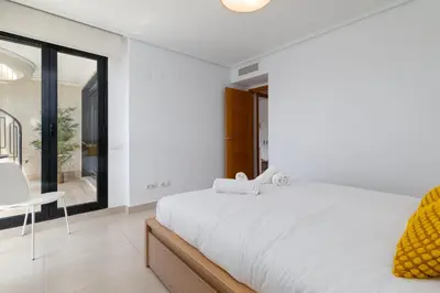 a white bedroom with a large bed and a window at ApartUP Patacona Sunrise Duplex I in Valencia