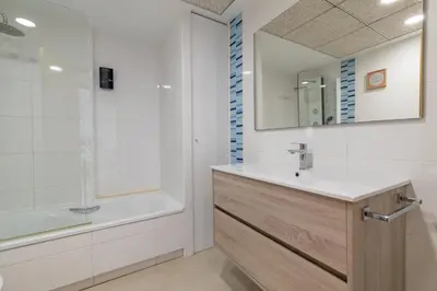 a bathroom with a sink and a tub and a mirror at ApartUP Patacona Sunrise Duplex I in Valencia