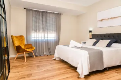 a bedroom with two beds and a chair and a window at El Labrador in Anna