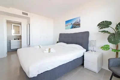a bedroom with a large white bed and a chair at Global Vacacional, Apartamento para 5 personas con terraza in Canet de Berenguer