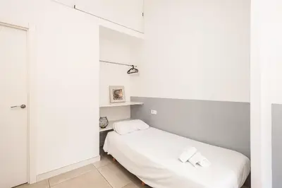 a white bedroom with a bed with two towels on it at El Mosaico Apartment in Valencia