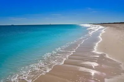 a beach with the ocean and blue water at Urban Beach in Valencia