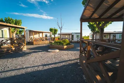 a wooden fence with a yard with houses at HolaCamp Chilches in Xilxes