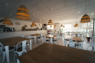 a restaurant with tables and chairs and pendant lights at HolaCamp Chilches in Xilxes