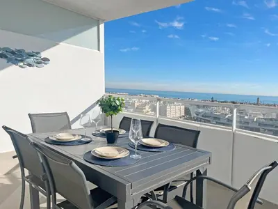 a dining table with chairs and a view of the ocean at Global Vacacional, Apartamento con amplia terraza con vistas al mar in Canet de Berenguer