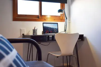 a desk with a laptop and a white chair at Departamento céntrico para disfrutar en familia in Sagunto