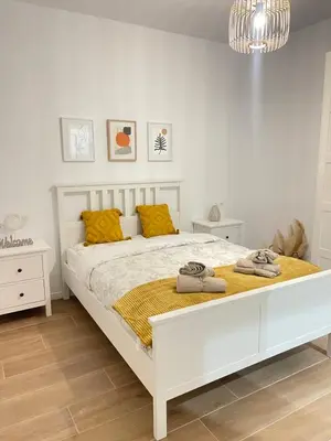 a bedroom with a large white bed with yellow pillows at UIM Mediterraneo CASA Sepulveda Wifi in Puerto de Sagunto