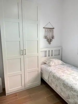 a white bedroom with a bed and a chandelier at UIM Mediterraneo CASA Sepulveda Wifi in Puerto de Sagunto