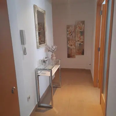 a hallway with a glass table and paintings on the wall at Apartamento San Vicente in Villar del Arzobispo