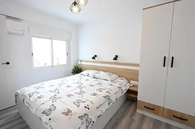 a white bedroom with a bed and a window at Victoria Apartment in Puerto de Sagunto