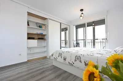 a white bedroom with a bed and a window at Victoria Apartment in Puerto de Sagunto