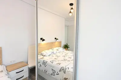 a bedroom with a bed with a mirrored wall at Victoria Apartment in Puerto de Sagunto