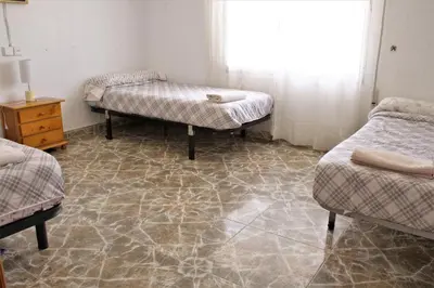 a room with three beds and a table and a window at Vacansis Habitaciones Privada en una Villa a un paso del Mar en Cullera in Cullera