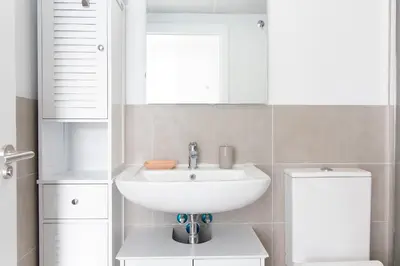 a white bathroom with a sink and a toilet at Global Vacacional, Apartamento para 5 personas con terraza y vistas a la piscina in Canet de Berenguer