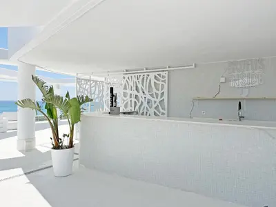 a white kitchen with a counter and a plant at Global Vacacional, Apartamento para 5 personas con terraza y vistas a la piscina in Canet de Berenguer