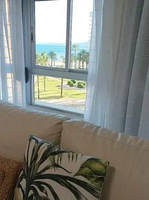 a couch with a pillow sitting in front of a window at Almar Collection Cullera AT in Cullera