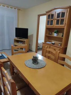 a room with a wooden table with chairs and a television at Precioso apartamento en Puerto de Sagunto Valencia in Puerto de Sagunto