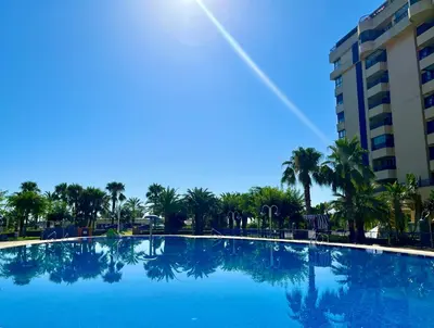 a large blue swimming pool with palm trees and a building at Blue Beach Apartment+Oceanview+Private Parking in Valencia